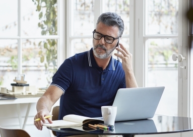 Businessman using mobile phone while writing notes